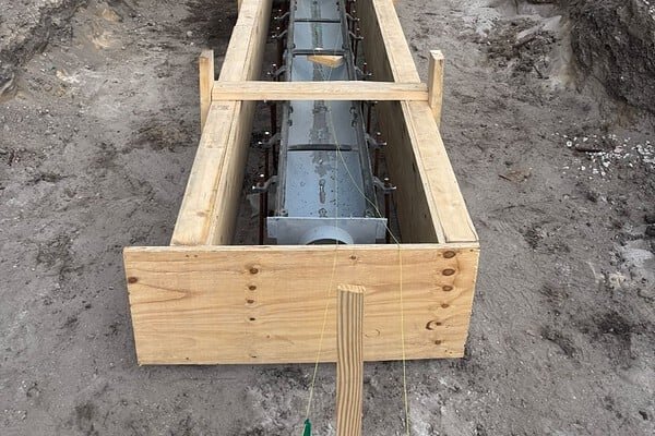 Forming a commercial trench drain during installation in West Palm Beach, FL, with an excavator working the trench
