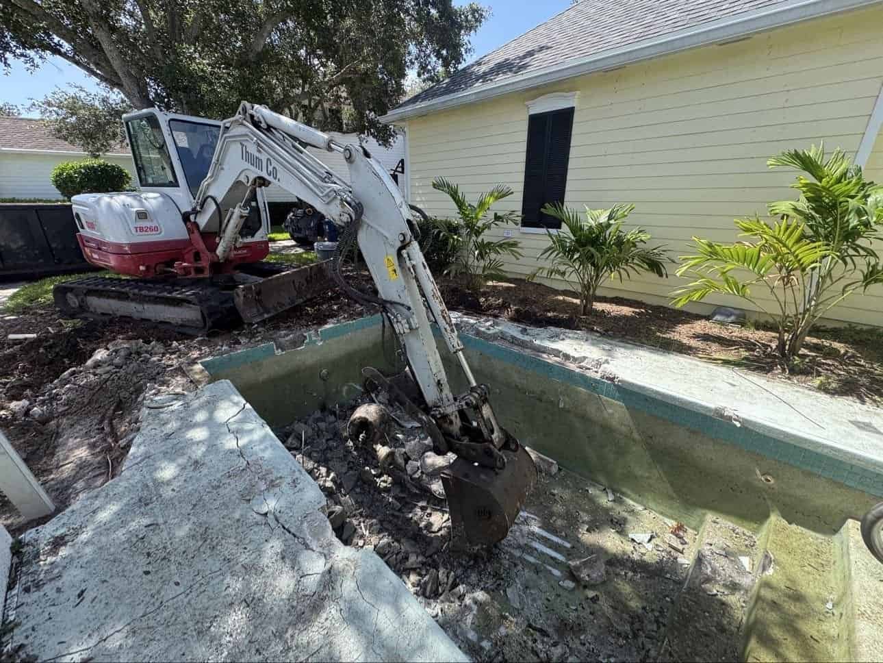 Excavator demolishing concrete pool in Jupiter Florida